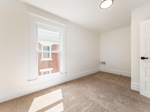 empty room featuring carpet floors, visible vents, and baseboards