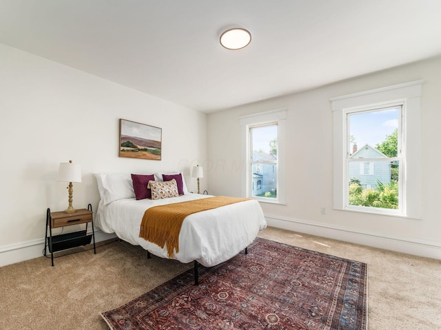 carpeted bedroom featuring multiple windows and baseboards