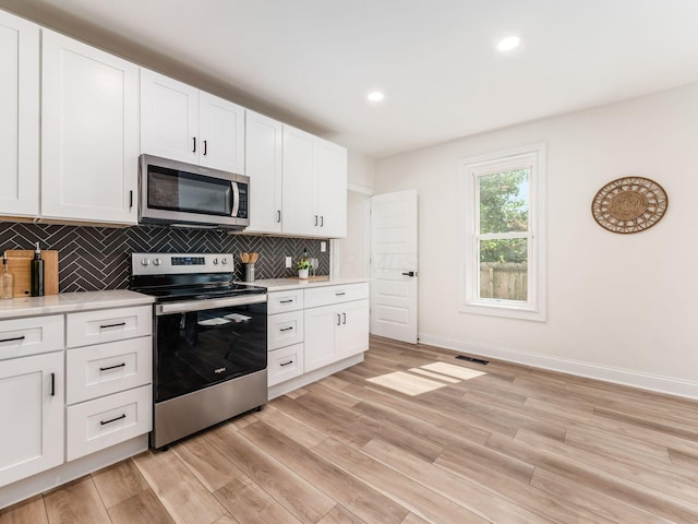 kitchen featuring stainless steel appliances, tasteful backsplash, light countertops, and light wood-style flooring