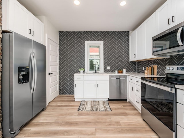 kitchen with stainless steel appliances, white cabinets, light countertops, and a sink