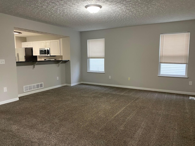 interior space featuring dark colored carpet, visible vents, and baseboards