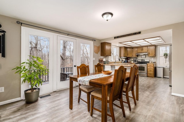 dining room featuring visible vents, light wood-style flooring, and baseboards