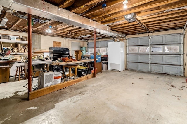 garage with a workshop area, a garage door opener, and freestanding refrigerator