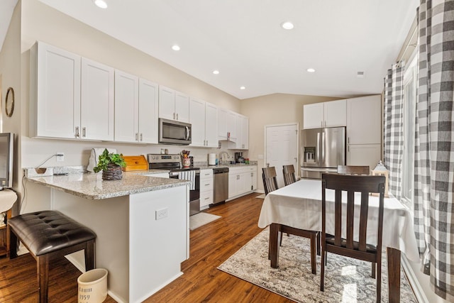 820 Timbers Edge, Marysville, OH 43040 - kitchen featuring stainless steel appliances, dark wood-type flooring, white cabinets, vaulted ceiling, and a peninsula