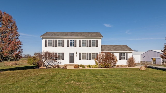 colonial home featuring a front yard and fence