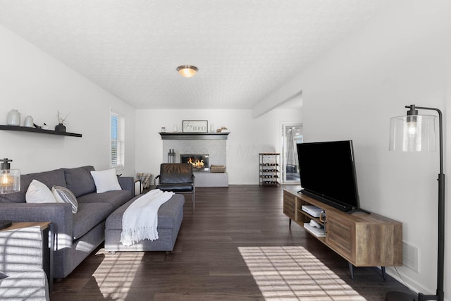 living area featuring a fireplace, visible vents, a textured ceiling, and wood finished floors