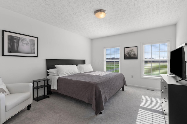 bedroom featuring light carpet, visible vents, baseboards, and multiple windows