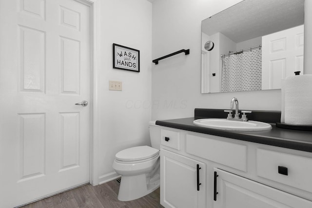 full bath with a textured ceiling, vanity, toilet, and wood finished floors