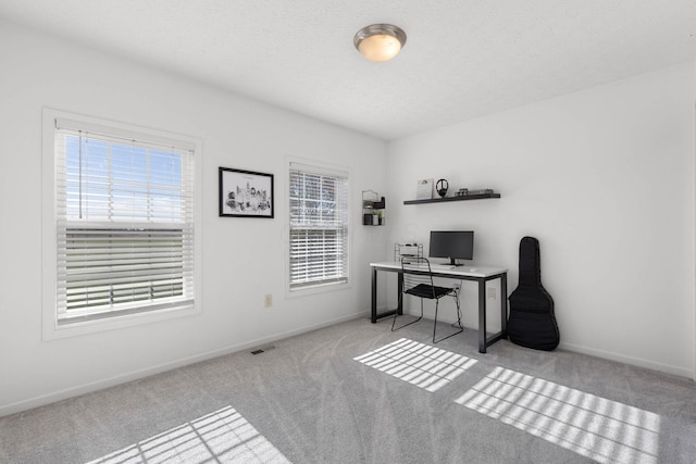 carpeted home office with visible vents, baseboards, and a textured ceiling