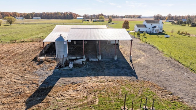 exterior space with a lawn, a rural view, a pole building, fence, and an outdoor structure