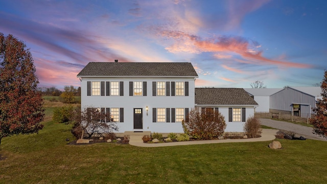 colonial house featuring driveway and a yard