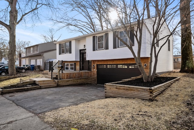 bi-level home featuring a garage and aphalt driveway