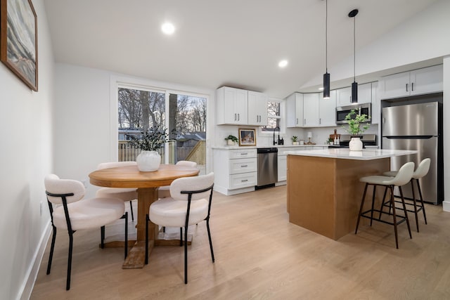 kitchen featuring a center island, stainless steel appliances, light countertops, light wood-style floors, and a kitchen breakfast bar