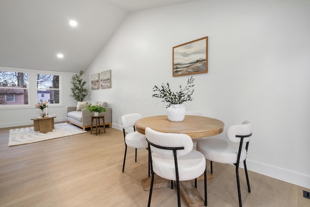 dining space with lofted ceiling, light wood-style flooring, and baseboards