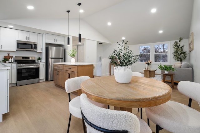 dining area featuring high vaulted ceiling, light wood-type flooring, and recessed lighting