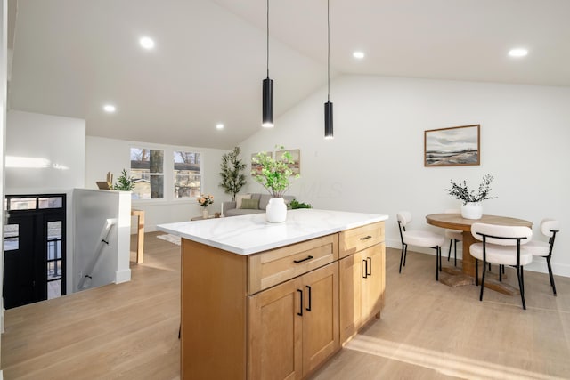 kitchen featuring light wood-type flooring, a center island, lofted ceiling, and light stone countertops