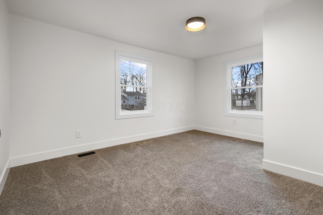 carpeted spare room with visible vents and baseboards