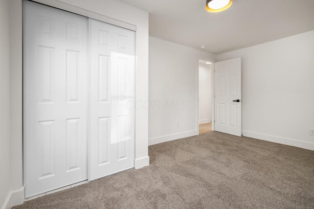 unfurnished bedroom featuring carpet, a closet, and baseboards