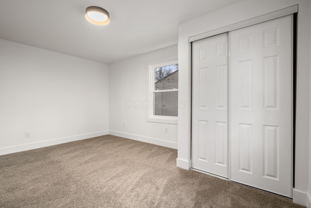 unfurnished bedroom with a closet, baseboards, and carpet flooring