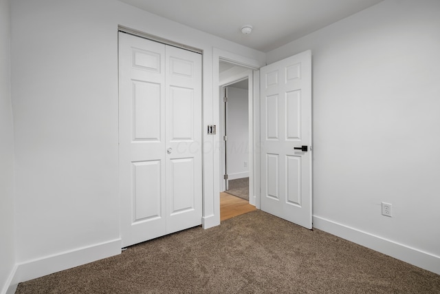 unfurnished bedroom with a closet, carpet flooring, and baseboards