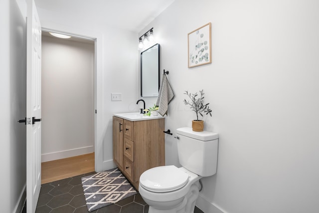 bathroom featuring toilet, tile patterned flooring, baseboards, and vanity