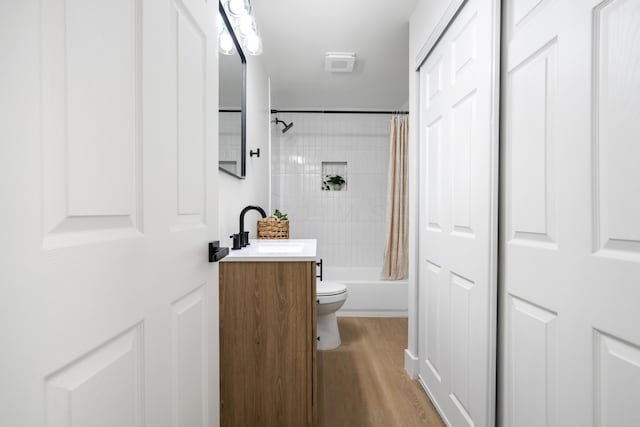 bathroom featuring toilet, wood finished floors, vanity, and shower / tub combo with curtain