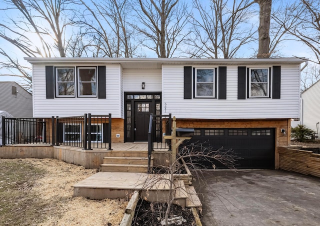 bi-level home featuring a garage and aphalt driveway