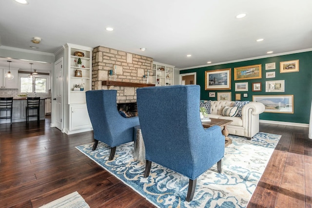 living room featuring recessed lighting, a stone fireplace, dark wood-style flooring, and crown molding