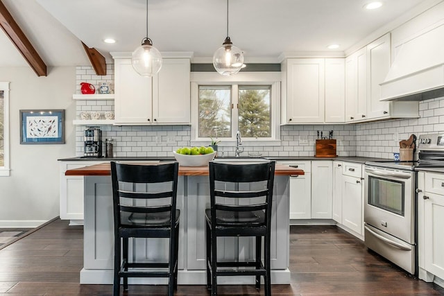 kitchen with custom range hood, a sink, dark wood finished floors, stainless steel range with electric cooktop, and a breakfast bar area