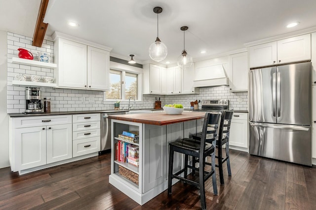 kitchen with butcher block countertops, appliances with stainless steel finishes, custom range hood, and open shelves