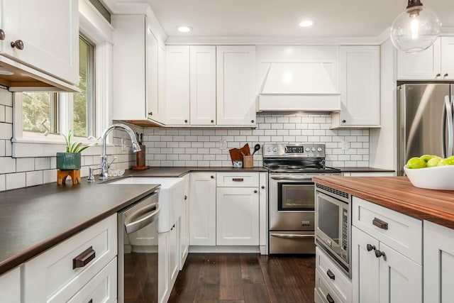 kitchen with custom range hood, a sink, dark wood-style floors, white cabinetry, and stainless steel appliances