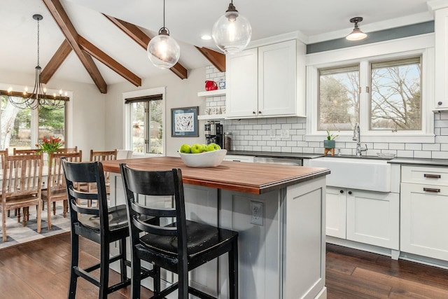 kitchen featuring tasteful backsplash, white cabinets, a kitchen breakfast bar, and dark wood-style flooring