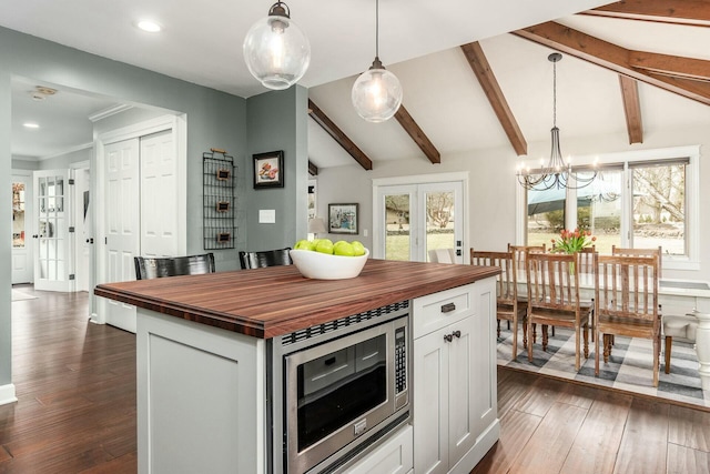 kitchen featuring lofted ceiling with beams, dark wood-style flooring, french doors, stainless steel microwave, and butcher block counters