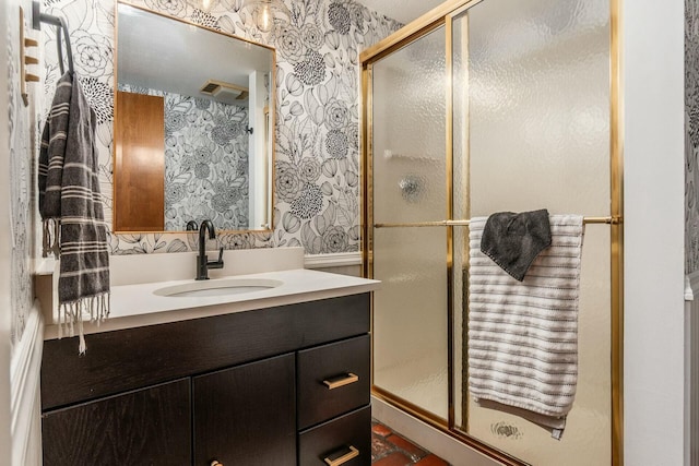 full bath with wallpapered walls, vanity, and a stall shower