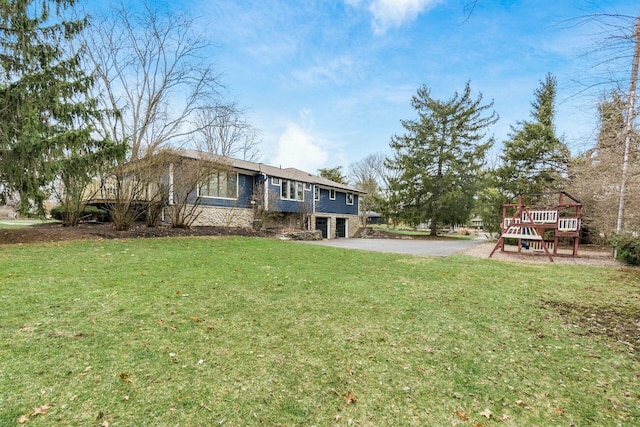 rear view of property with a yard, a garage, and driveway