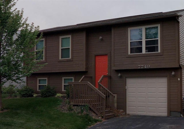 split foyer home with a front lawn, driveway, and an attached garage