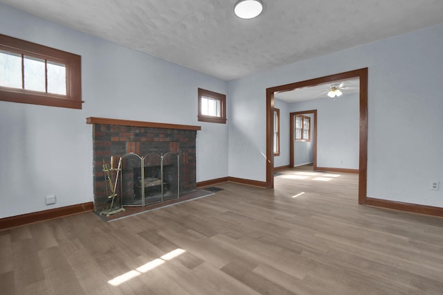 879 Mansfield Ave, Columbus, OH 43219 - unfurnished living room featuring a brick fireplace, wood finished floors, and baseboards