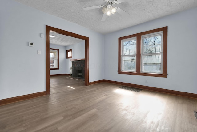 879 Mansfield Ave, Columbus, OH 43219 - unfurnished room featuring a fireplace with flush hearth, plenty of natural light, wood finished floors, and visible vents