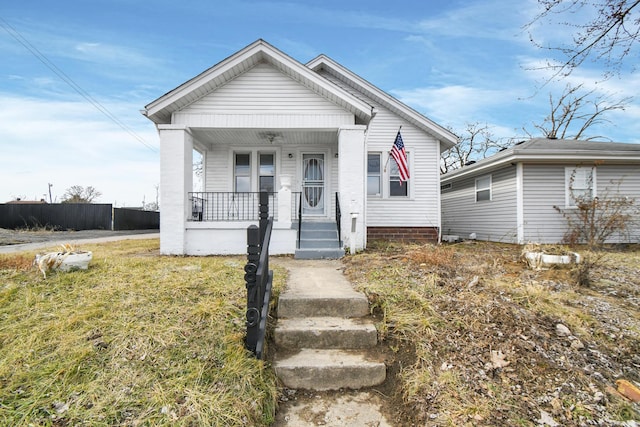 bungalow-style house featuring a porch, a front lawn, and fence