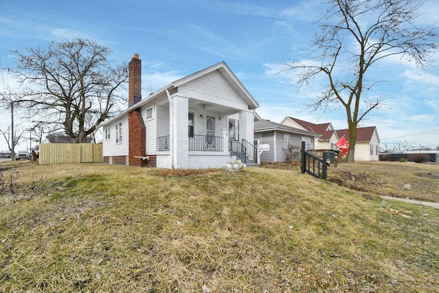 view of front of home featuring a porch, a chimney, a front yard, and fence