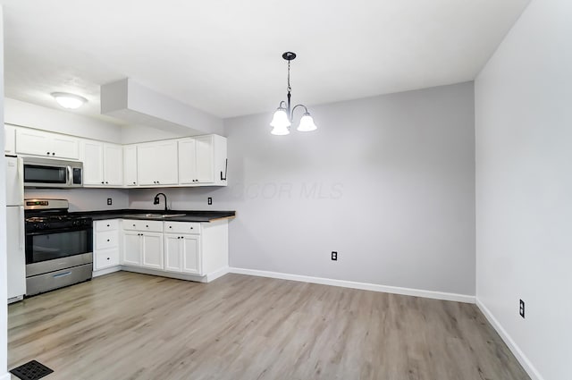 kitchen with stainless steel appliances, dark countertops, light wood-style flooring, a sink, and baseboards