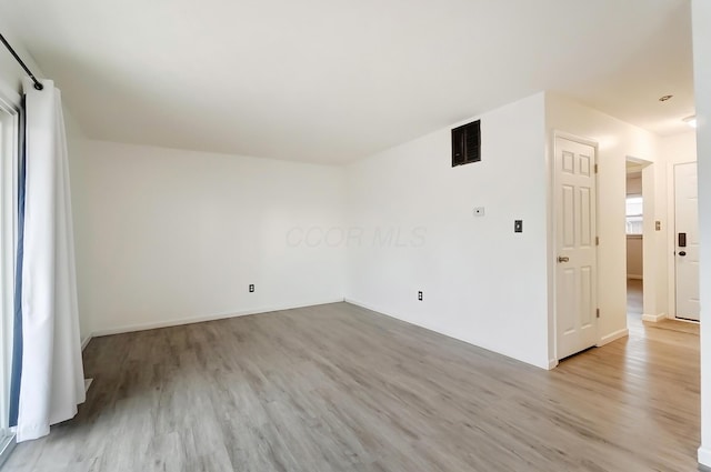 spare room featuring light wood finished floors and visible vents