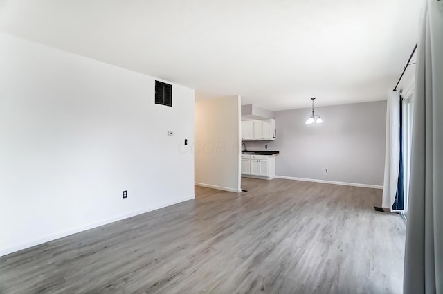 unfurnished living room with light wood-style flooring, visible vents, and baseboards