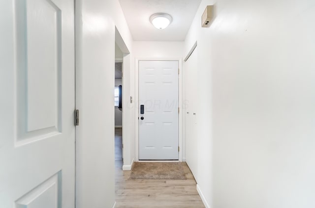 doorway featuring light wood finished floors and baseboards