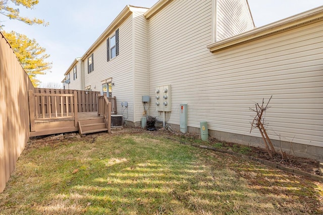 view of side of home with cooling unit, a yard, and a wooden deck