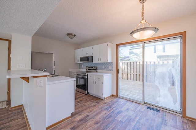 kitchen with stainless steel appliances, white cabinetry, a sink, and wood finished floors