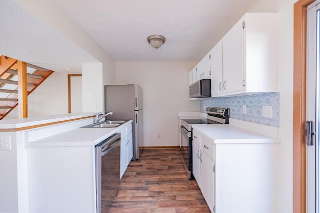 kitchen featuring wood finished floors, a sink, white cabinets, light countertops, and appliances with stainless steel finishes