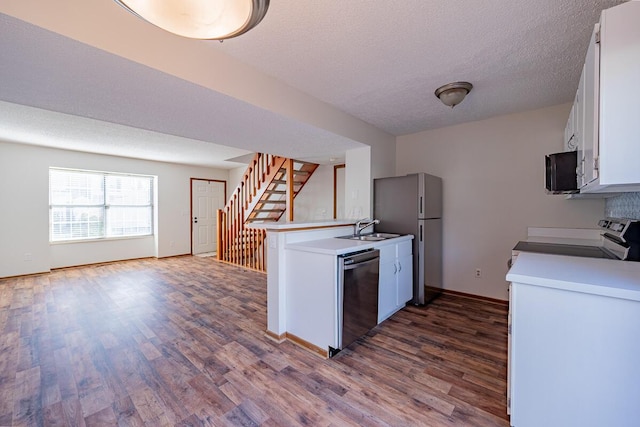 kitchen featuring dishwashing machine, electric range, dark wood-style floors, and freestanding refrigerator