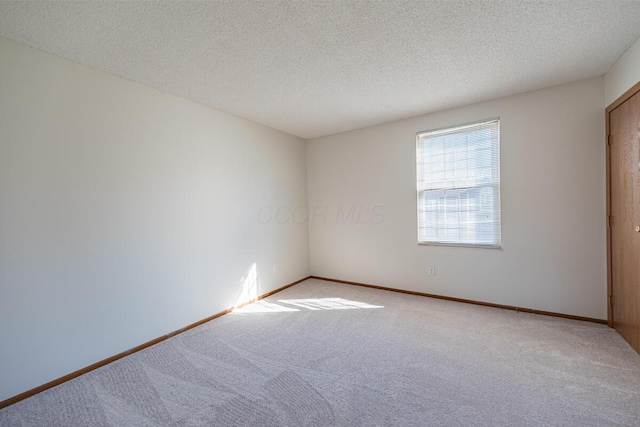 carpeted empty room featuring a textured ceiling and baseboards