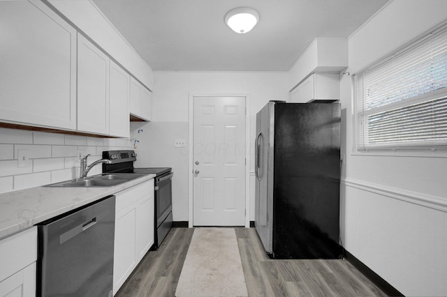 kitchen with white cabinets, wood finished floors, a sink, stainless steel appliances, and backsplash